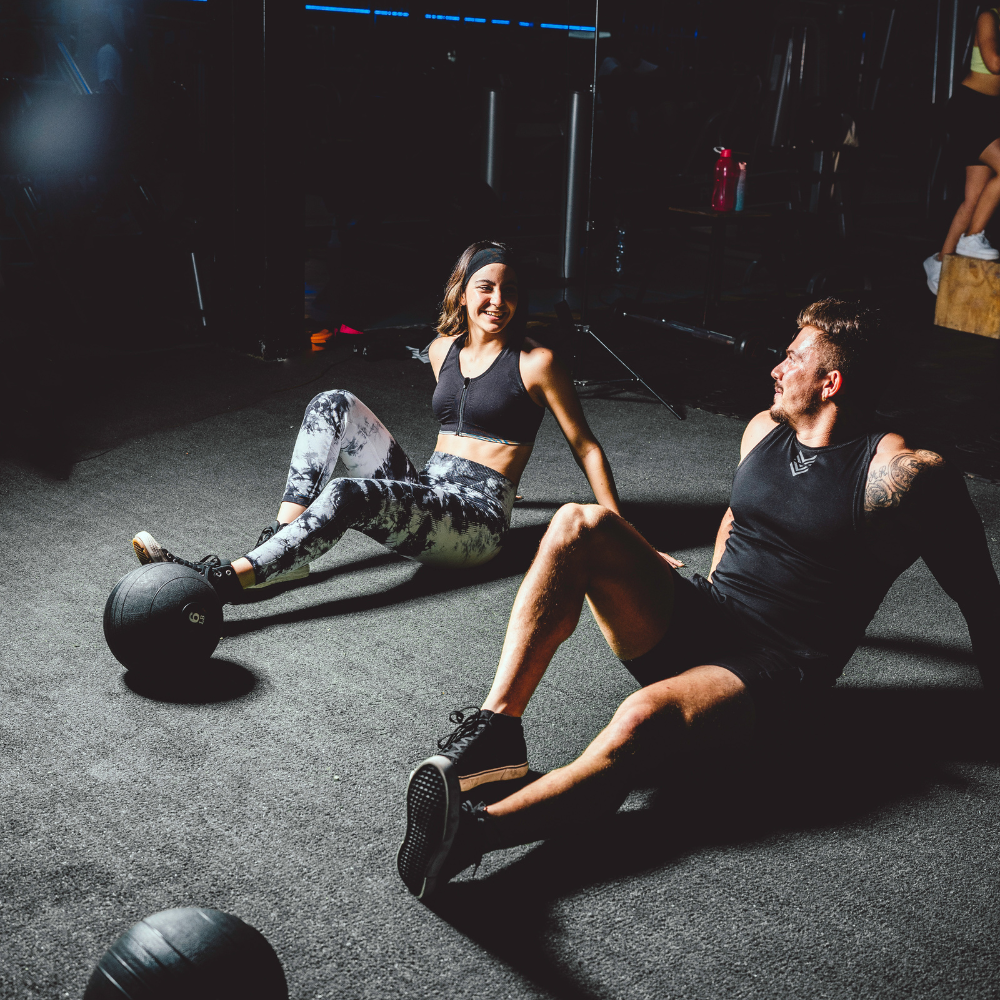 Two people exercising with medicine balls in a gym setting